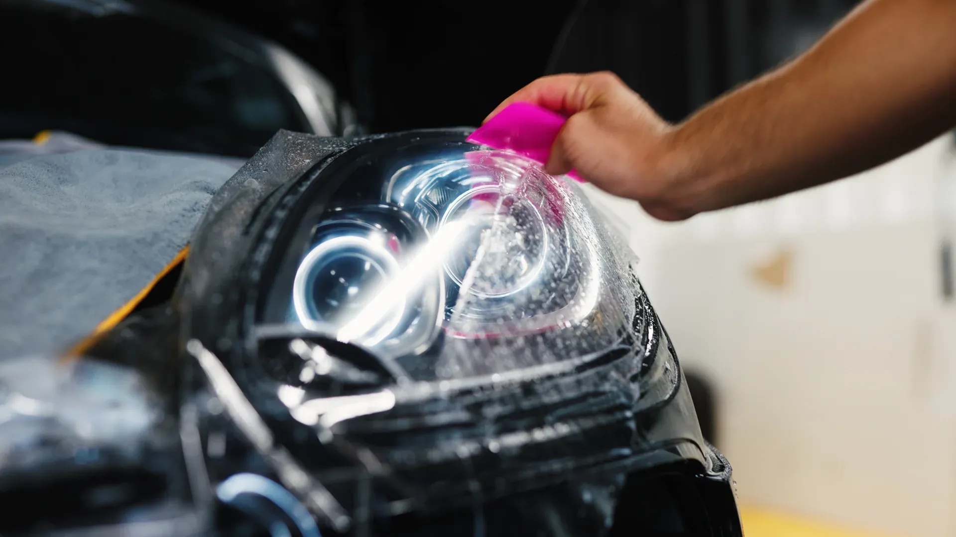 Close-up of paint protection film being applied to a vehicle headlight.