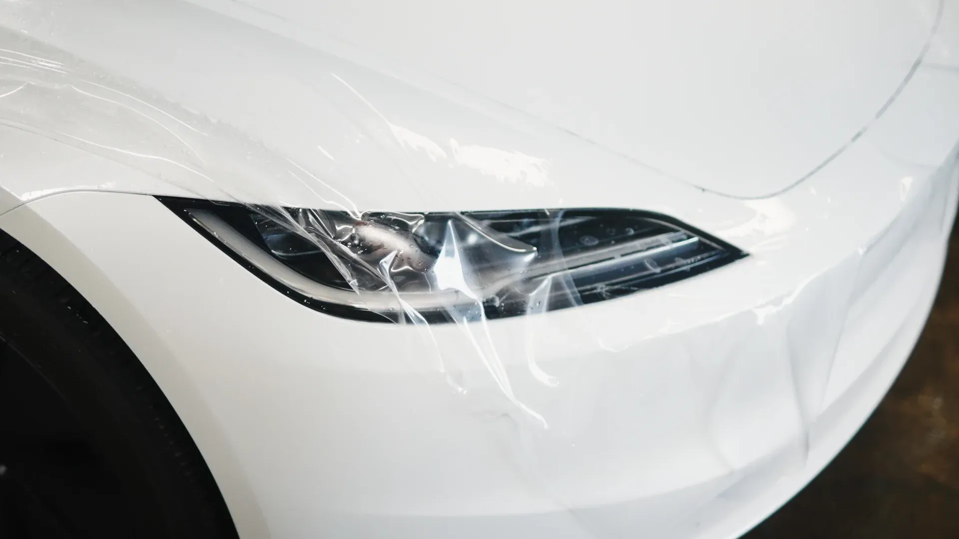Paint protection film laid across a white vehicle headlight.