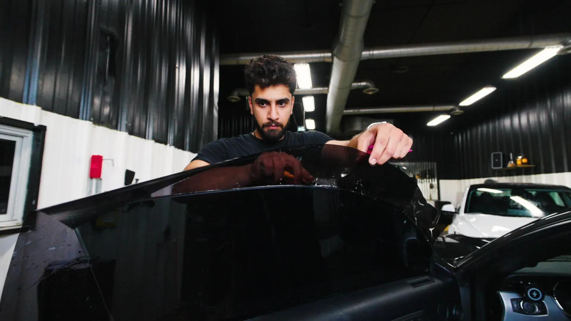 Tint My Ride technician holding prepared window tint film inside the shop.