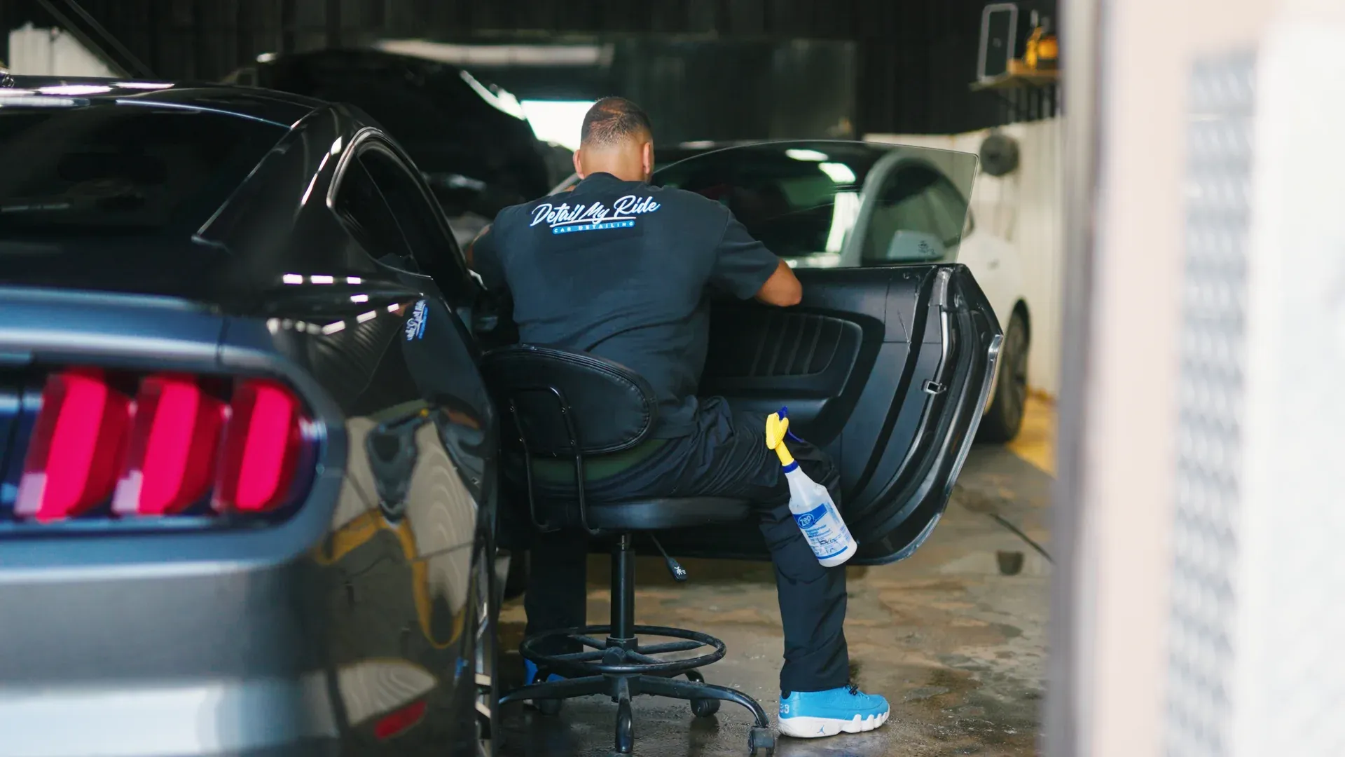 Technician installing window tint from inside a vehicle.