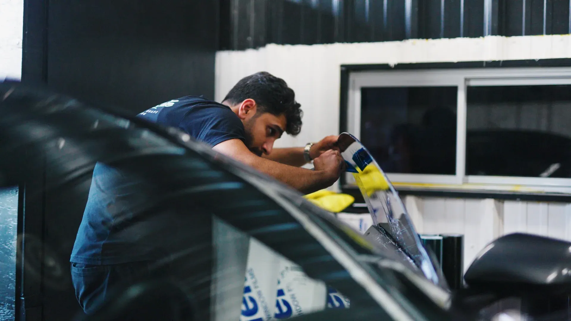 Technician installing tint film on a vehicle side window.